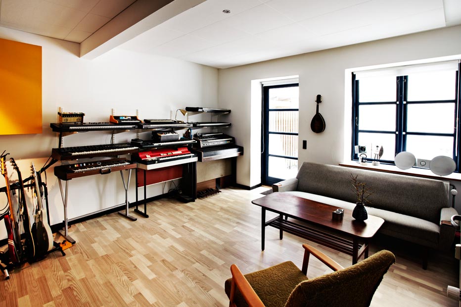 Music studio with keyboards, synthesizers, organs, guitars, sofa and chair 